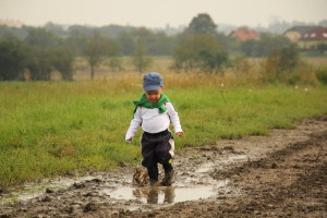 a little boy likes to run and jump in a puddle